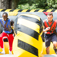 Two male students running on obstacle course