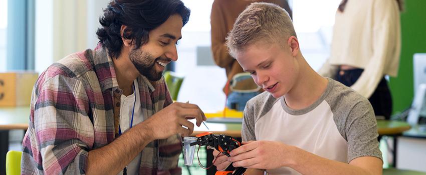 A man helping a younger student on a project