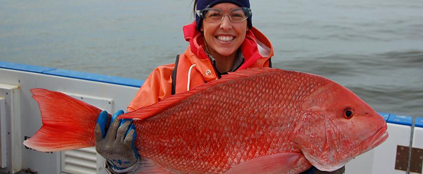 Student holding fish on boat