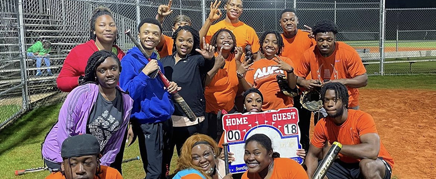 Students at baseball game holding bats.