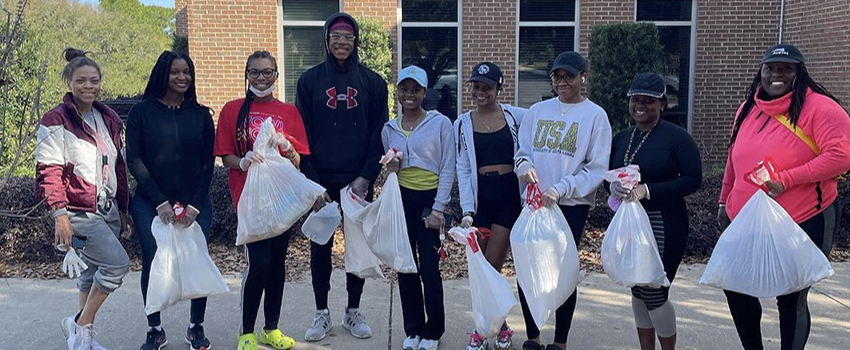 Students outside of the student center holding trash bags.