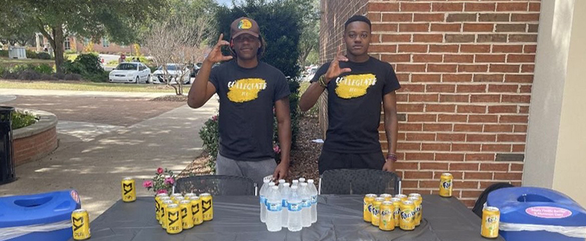 Two fraternity members at a table outside the Student Center,