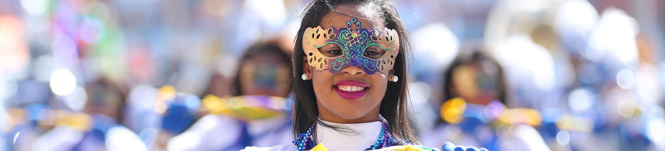 Female in mask marching in mardi gras parade.