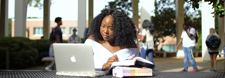 Student outside of Humanities Building working on computer