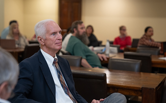 close up of faculty member with other out of focus in the background listening to speaker