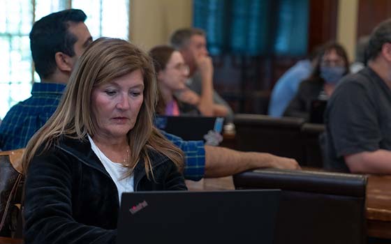 faculty member taking notes on computer during presentation