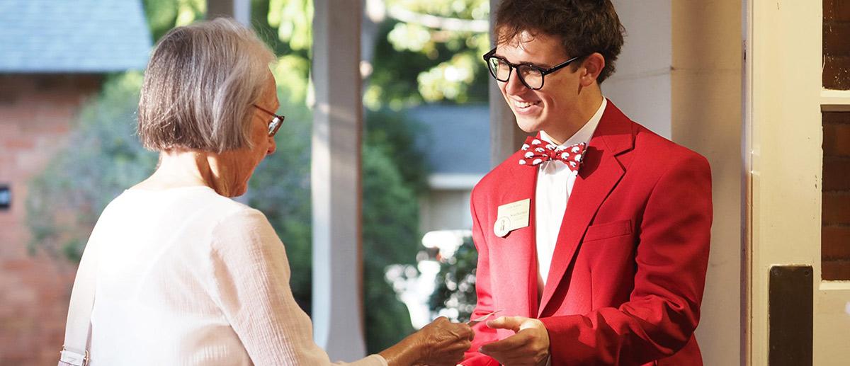 Southerner smiling taking a card from a woman in white outfit.