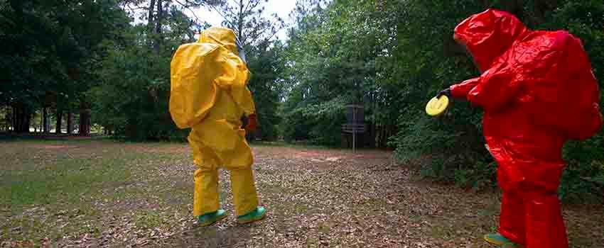 Two men in hazmat suits in disc golf courseTwo men in hazmat suits in front of storage container