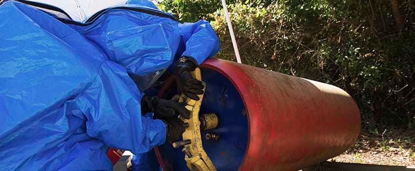 Two men in hazmat suits working with valve