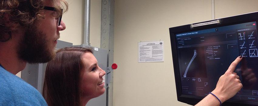 Male and female student looking at monitor