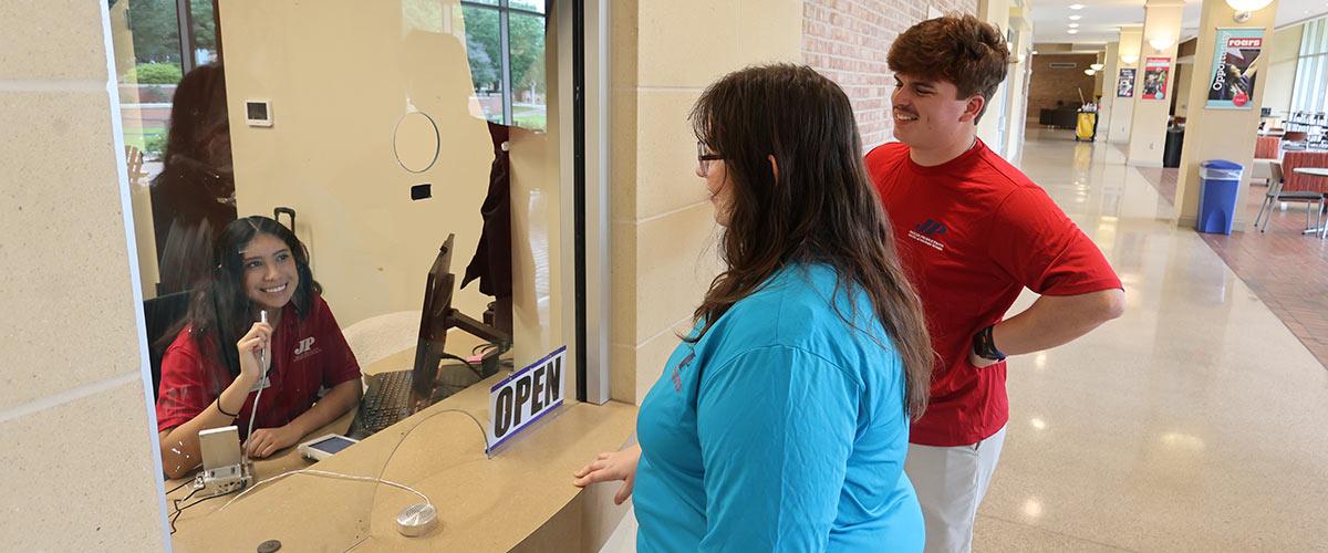 Students talking with Student worker at Jaguar Production window.