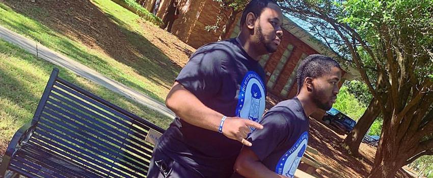 Two NPHC Students in front of greek benches 