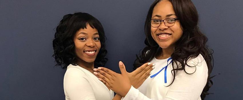 Two female NPHC Students holding up Greek sign