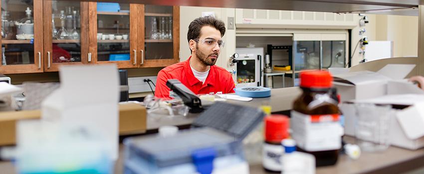 Male student with safety glasses on in a lab.