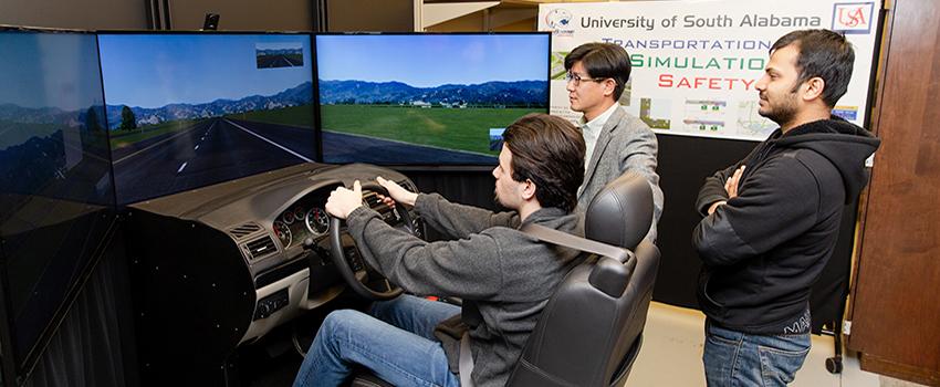 Civil Engineering students using the driving simulator with professor.