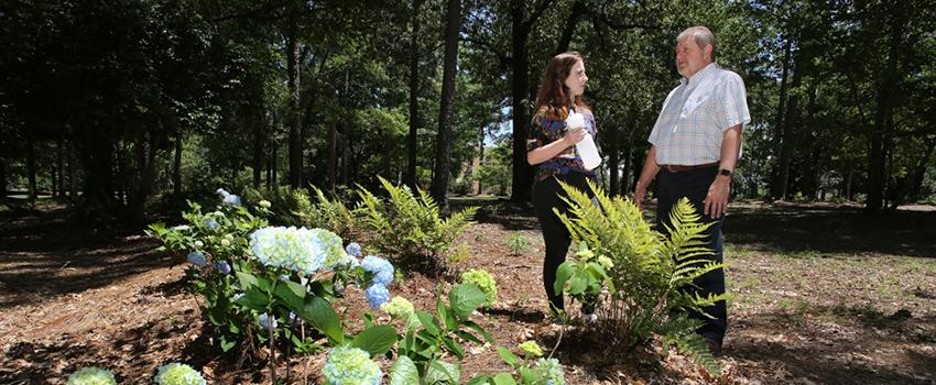 Dr. Kevin White, right, professor and chair of the department of civil, coastal and environmental engineering, and Jordan Blackmon, sophomore civil engineering major, stand on the edge of one of five landscaped bioinfiltration swales near Meisler Hall. The swales help capture storm water runoff instead of it running off on the surface and eroding soil that eventually deposits into Three Mile Creek.