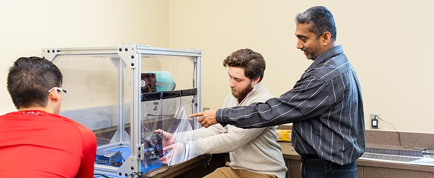 Electrical Engineering Professor pointing at machine students are working on.