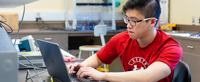 Male student working on laptop in lab.