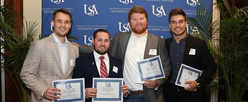 Four male students holding their engineering scholarship certificates.