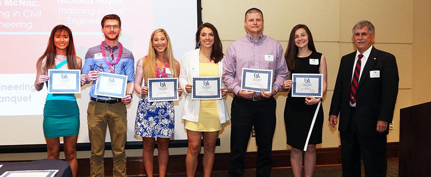 Dr. Steadman with two male and four female students holding their engineering scholarship certificates.