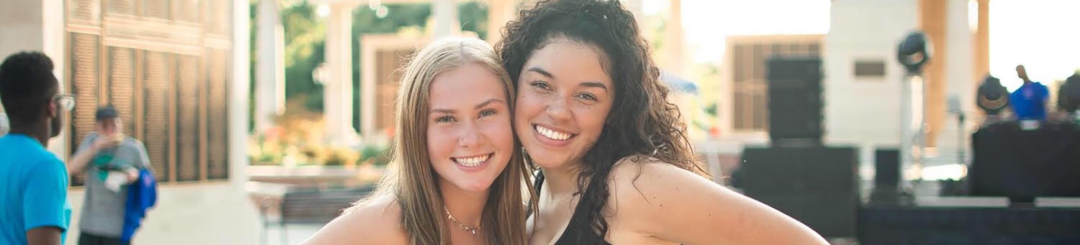 Two female students smiling outside