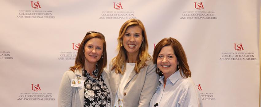 Three female instructors in front of USA backdrop