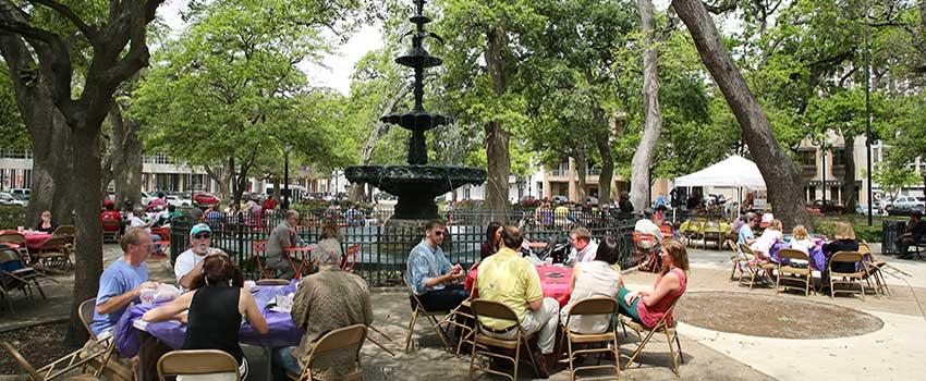 People gathered downtown at tables around fountain at Bienville Square.