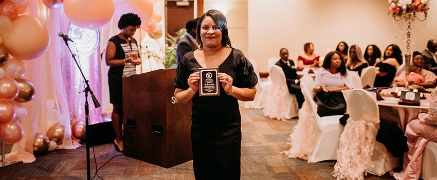 Woman Poses for a picture after receiving her plaque