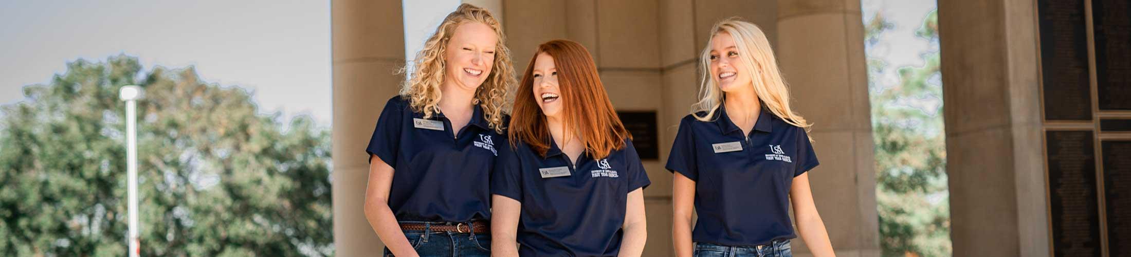 Three female FYC members smiling outside under Moulton Tower.