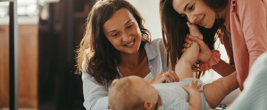 Two women smiling and playing with baby