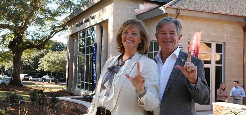 Mr and Mrs Macqueen holding up j sign