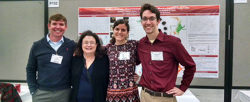 Group of Geology students in front of a project with a professor.