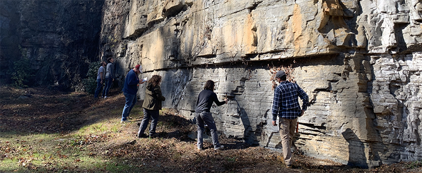 Geology students studying rocks outside.