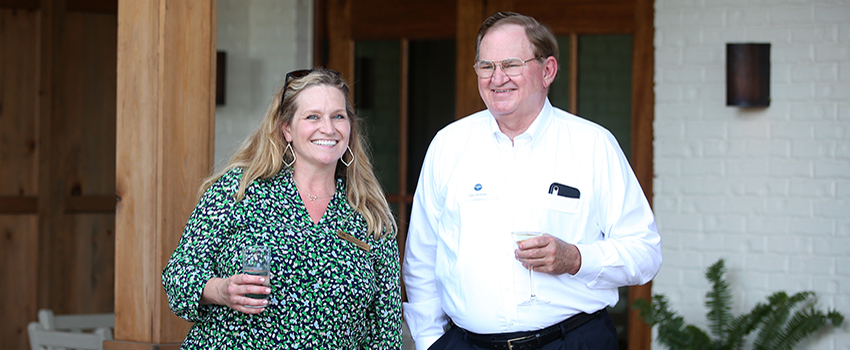 Man and woman smiling in front of Hope Farm.