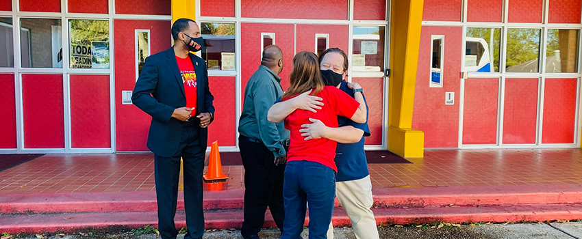 People hugging receiving classroom materials.