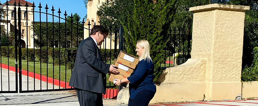 Woman shaking hands receiving classroom materials in front of Murphy High School.