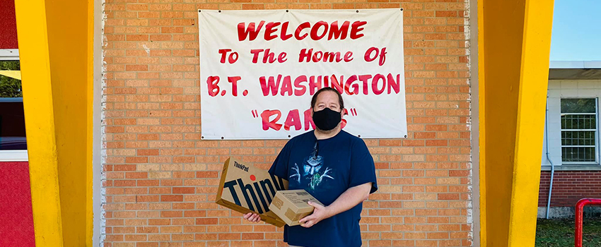 Man holding classroom materials in front of BC Raines.