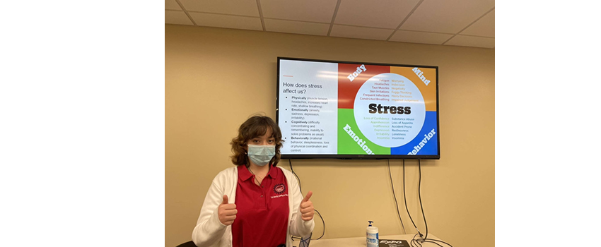 Student in front of screen with a presentation in the background about stress.