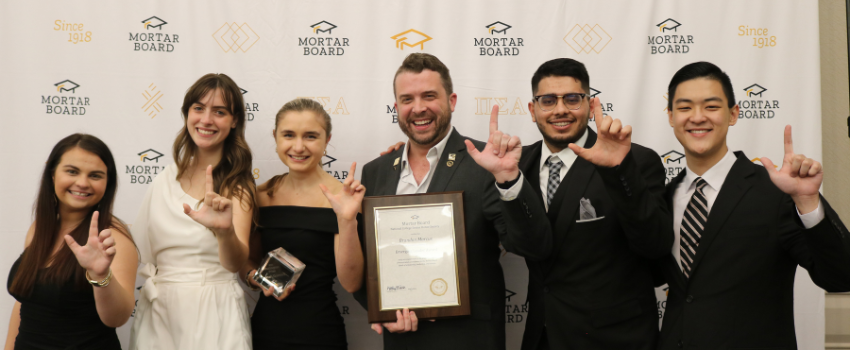 Mortar board group holding award and holding up J symbol.