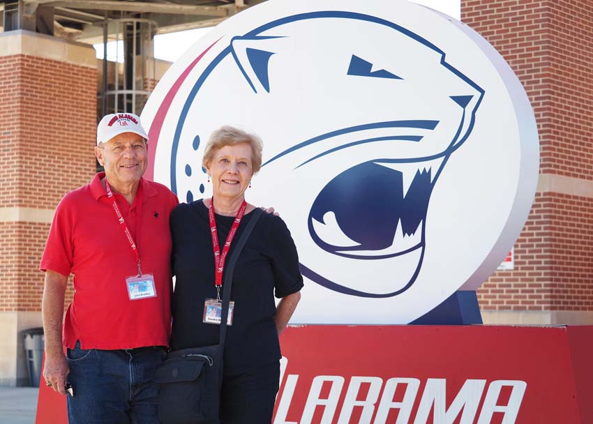 Two people in front of Jaguar sign.