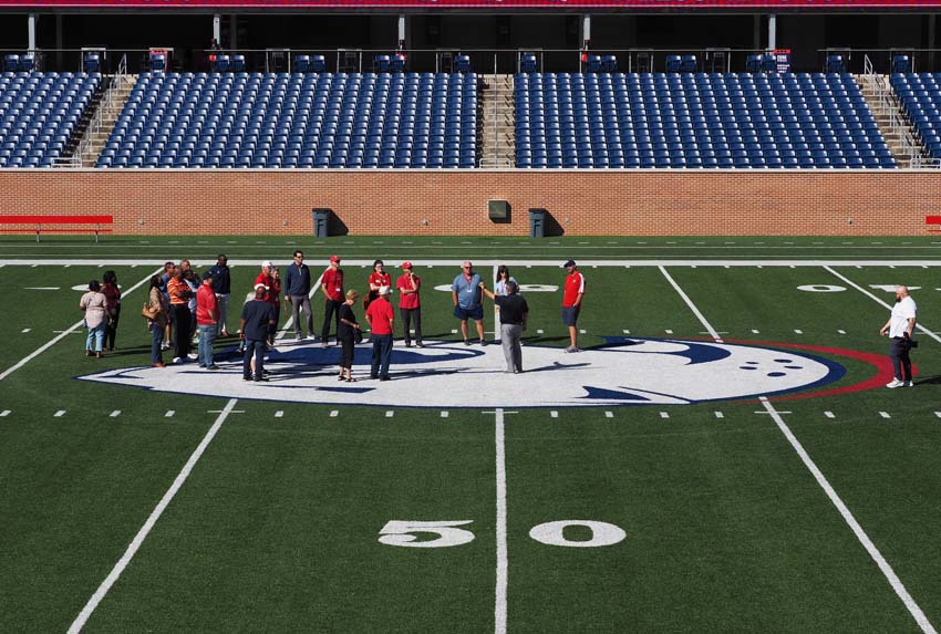 Group on jaguar head on football field.