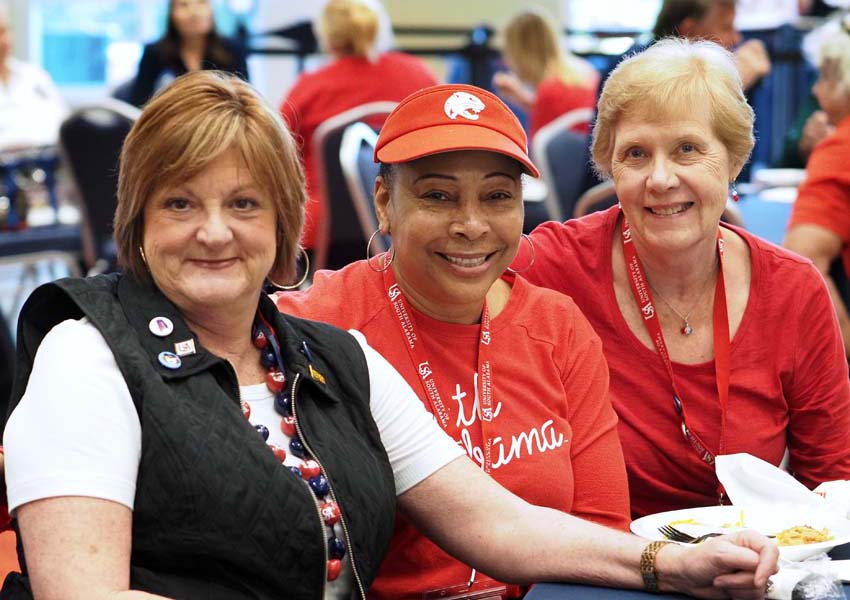 Three women smiling at event.