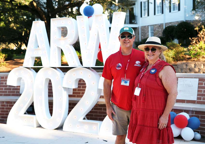 Alumni Reunion Weekend sign with two alumni couple in front of it.