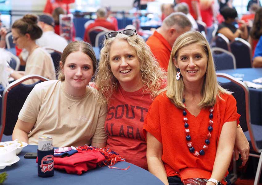 Three people at alumni event smiling.