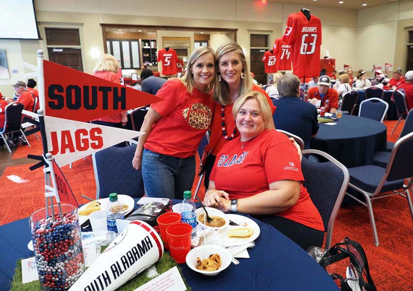 Alumni sitting at table with jag flags.