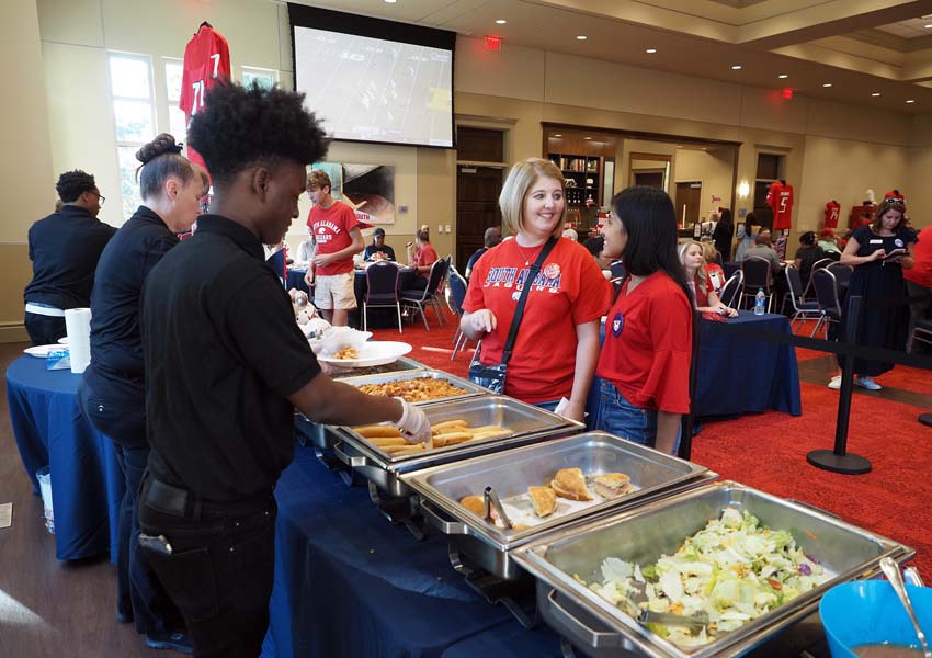 People getting food at alumni event.