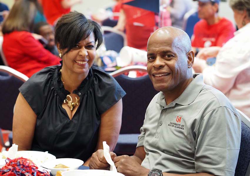 Couple smiling at alumni table.