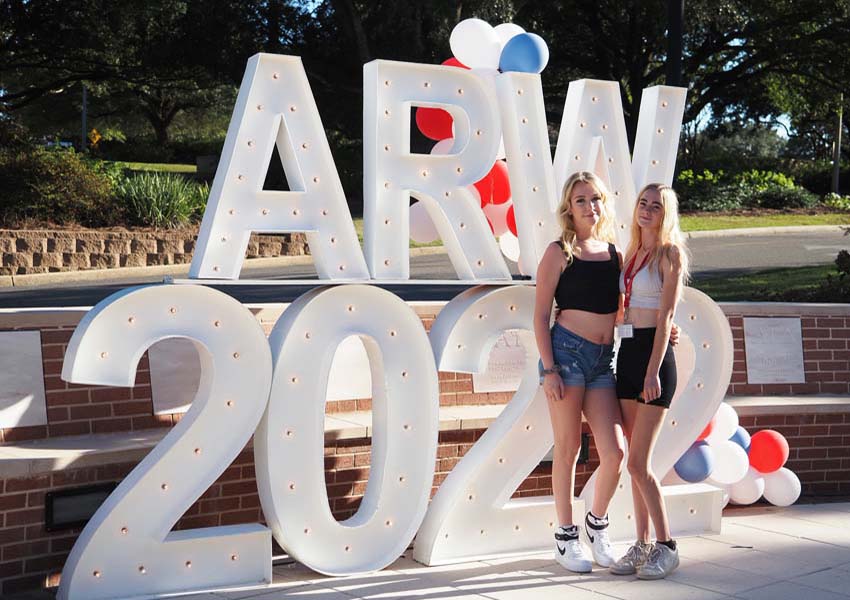 Two young girls in front of Alumni Reunion Weekend sign.