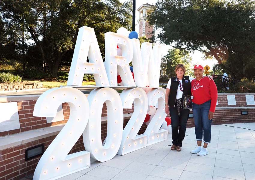 Alumni Reunion Weekend sign with two alumni members in front of it.