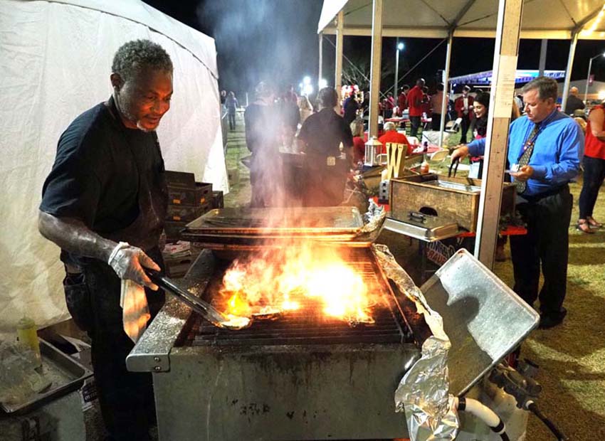 A worker flips burgers at the All Class Party 2022